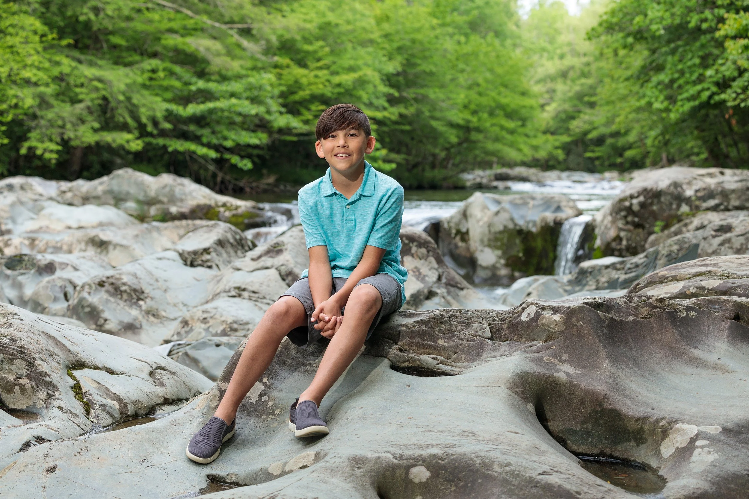 Young boy sitting on rocks by a river in the Great Smoky Mountains National Park.
