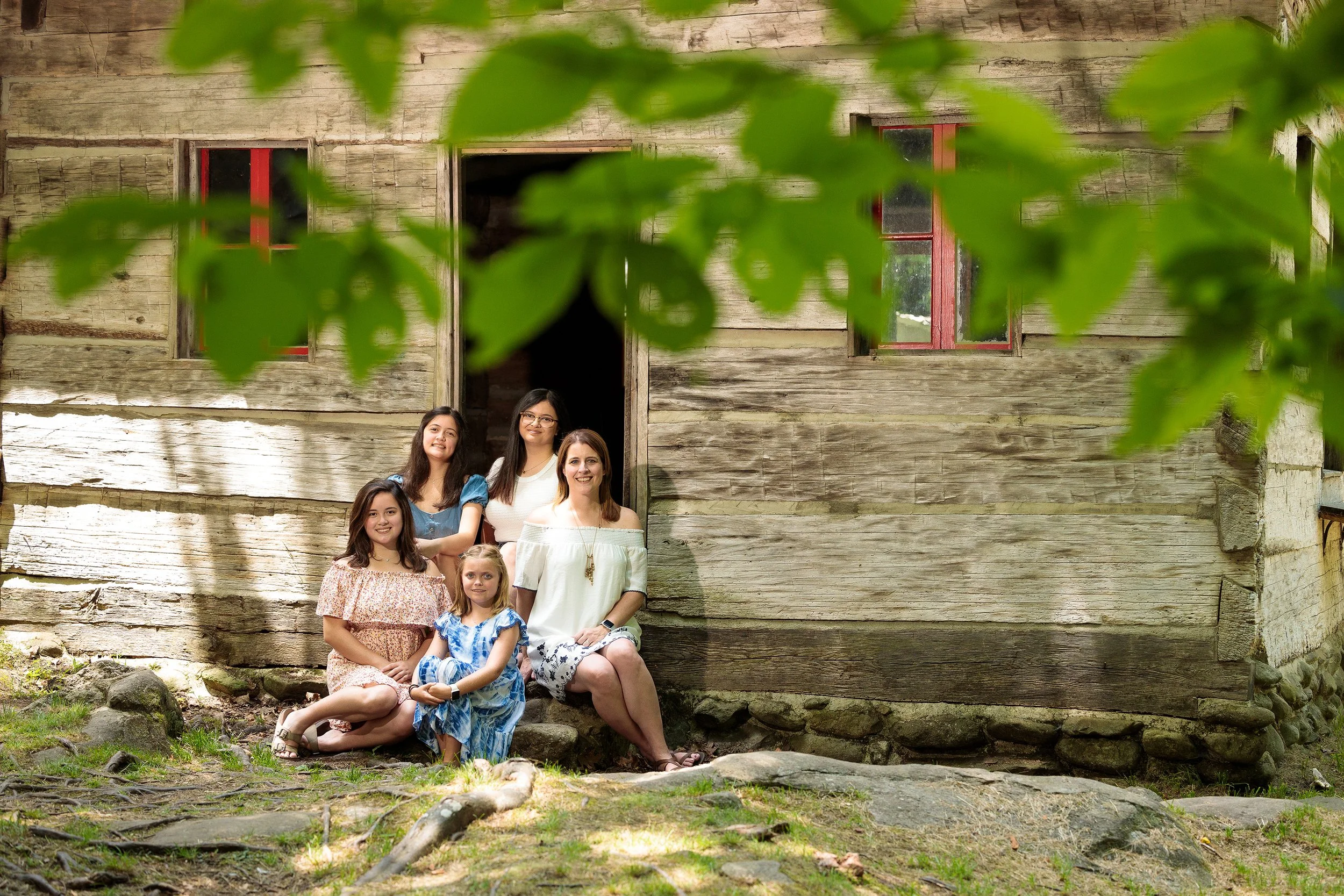 A mother and her daughters sitting in front of an old cabin in the Great Smoky Mountains National Park.