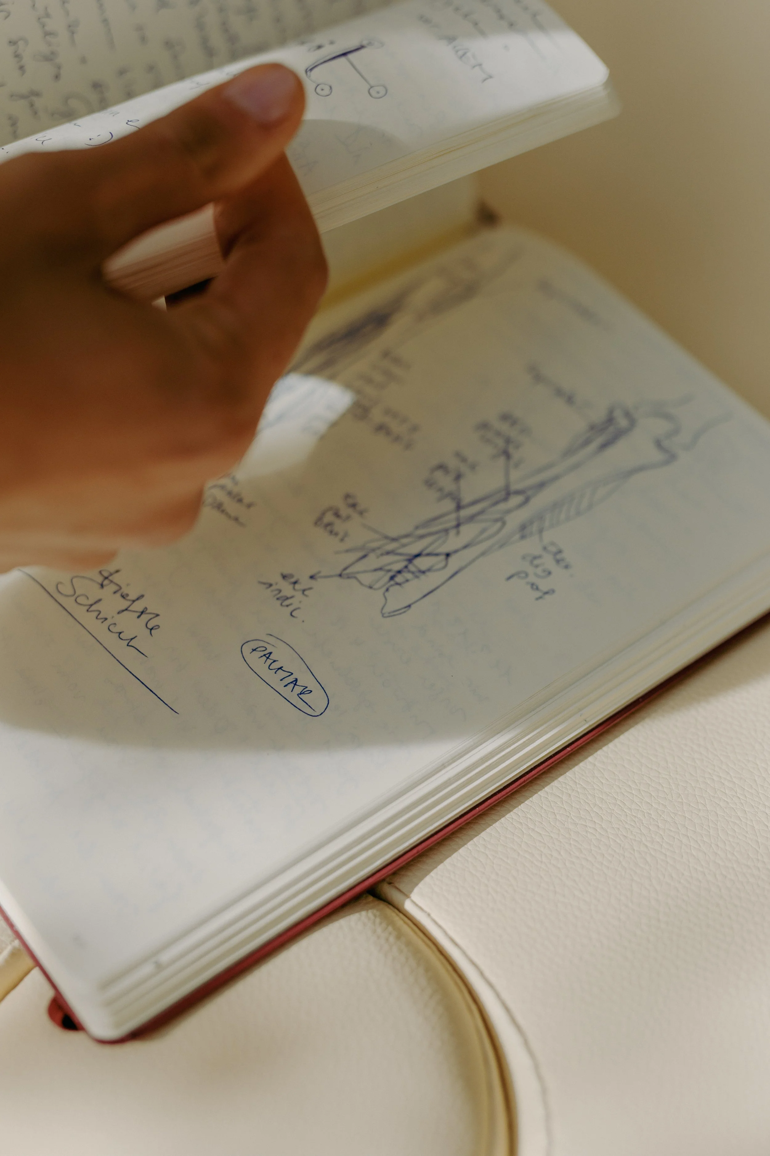 Ein Notizbuch mit handschriftlichen Skizzen und Notizen, das auf einem weißen Tisch liegt.