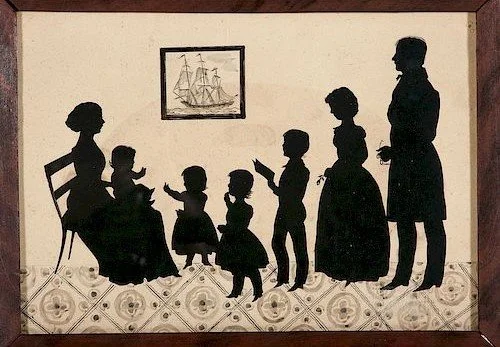 Silhouette art depicting a family scene with seven people, including children and adults, in a room with a framed ship picture on the wall and patterned flooring.