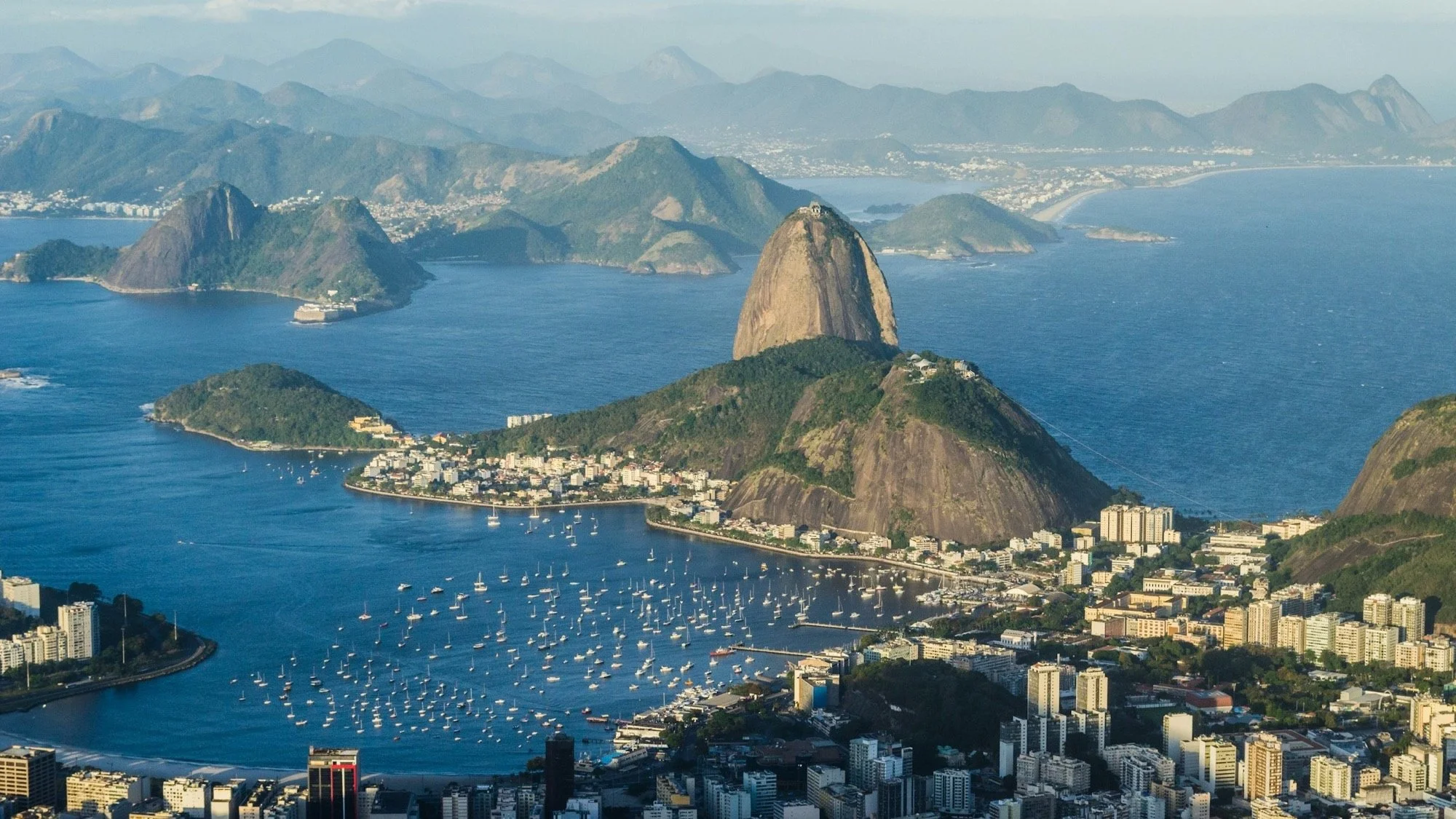 Sugarloaf Mountain rising over Botafogo Bay and its moored sailboats in warm late afternoon light, Rio de Janeiro.