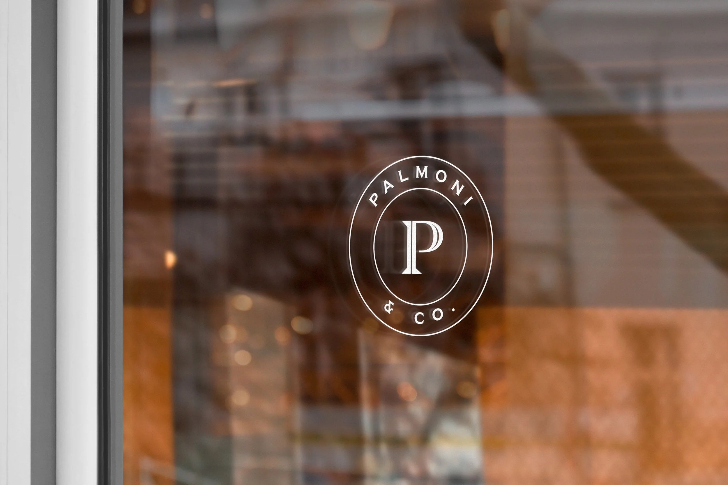 Close-up of a glass door with a circular logo that reads 'PALMONI & CO' and a large letter 'P' inside the logo. The background shows a blurred wooden floor and furniture.