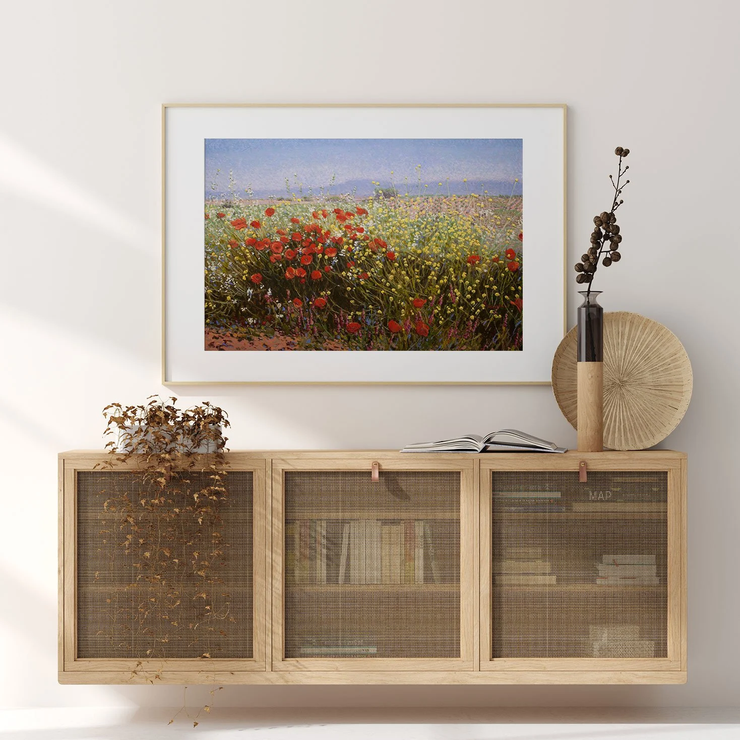 Sala de estar com quadro de campo de flores na parede e móveis de madeira com objetos decorativos, incluindo um vaso com galho seco e uma peça decorativa redonda.