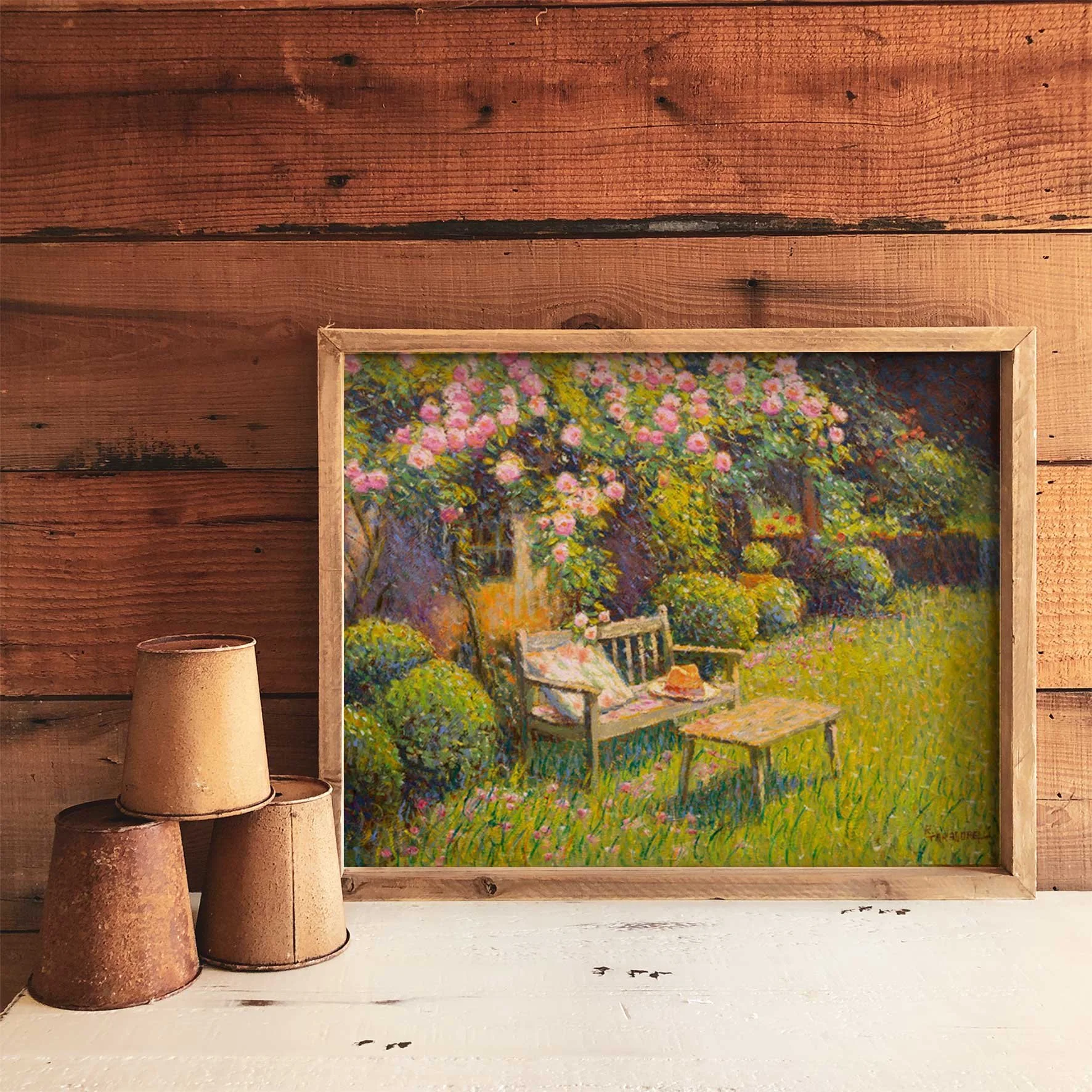 Quadro com pintura de um jardim com árvores e flores em tons de rosa, verde e azul, apoiado numa parede de madeira e acompanhado de três vasos de barro de diferentes tamanhos na frente.