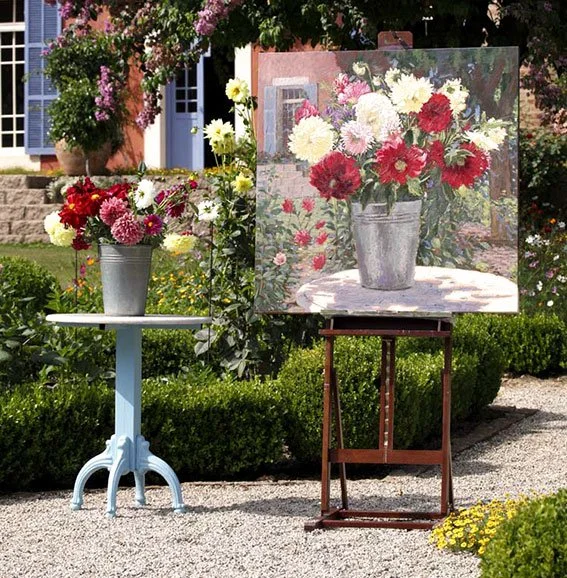 Quadro de uma pintura de flores em vaso, exibido ao ar livre entre flores e arbustos