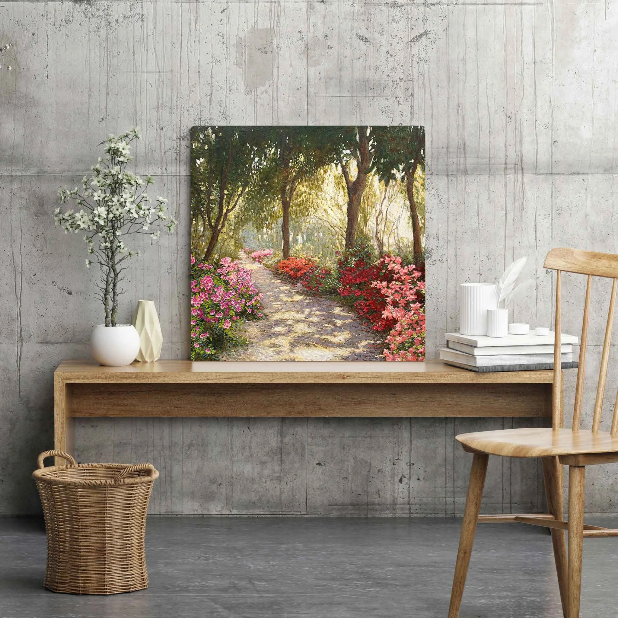 Sala de estar com parede de concreto, decorada com pintura de um caminho em um parque com árvores e flores. Há uma mesa de madeira com vasos de plantas brancas, cadeira de madeira, cesta de vime e objeto branco ao lado.
