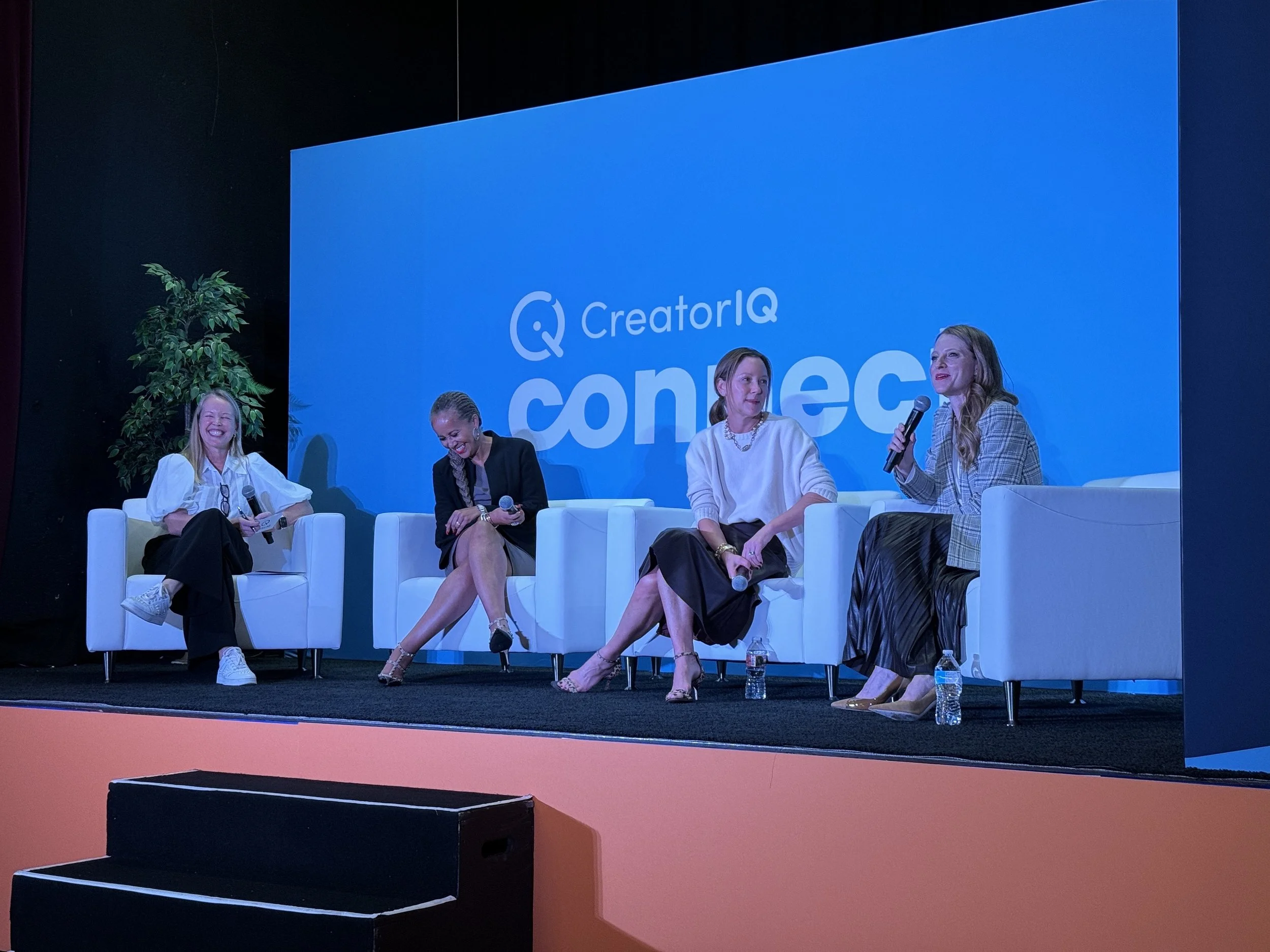 Four women sitting on stage in front of a blue screen with the logo 'CreatorIQ' and the word 'connect'. Max Powers is leading a panel discussion about women in leadership.