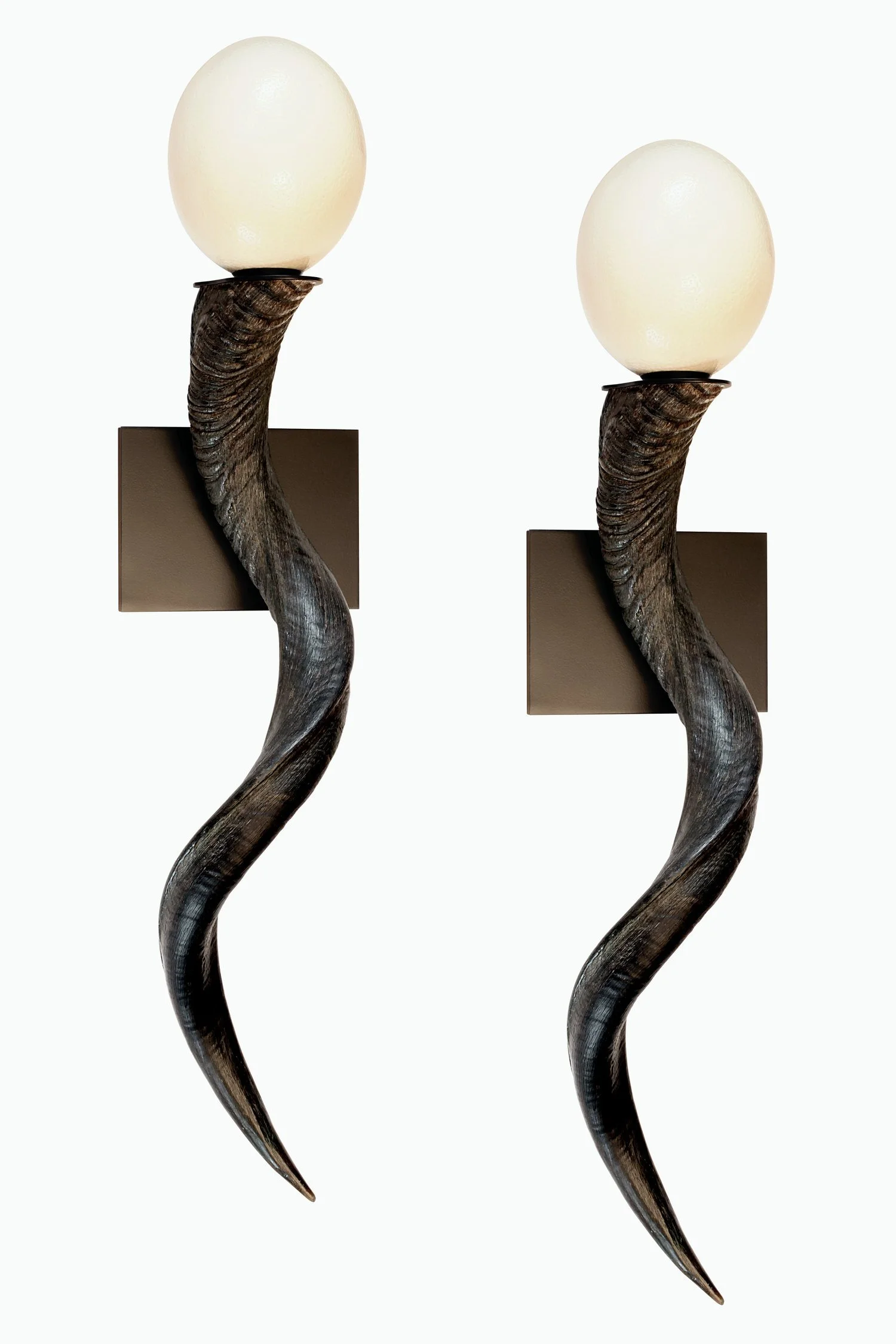 A modern wall-mounted lamp with a white spherical glass shade, supported by a curved, dark-toned metal arm attached to a rectangular wall mount.