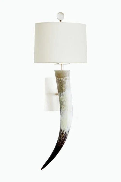 Wall-mounted lamp with a white lampshade and a decorative horn base.