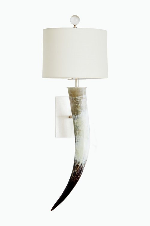 Wall-mounted lamp with a white lampshade and a base made from a faux animal horn.