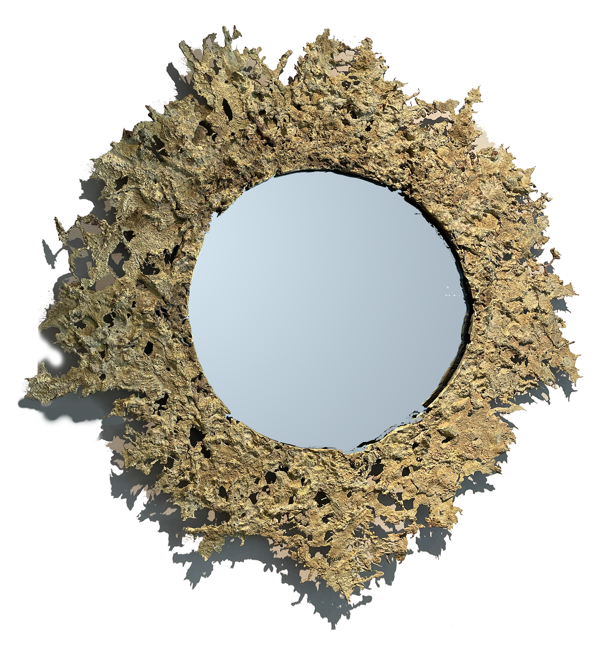 Close-up of a circular mirror surrounded by a rugged, gold-colored frame with a textured, organic appearance.