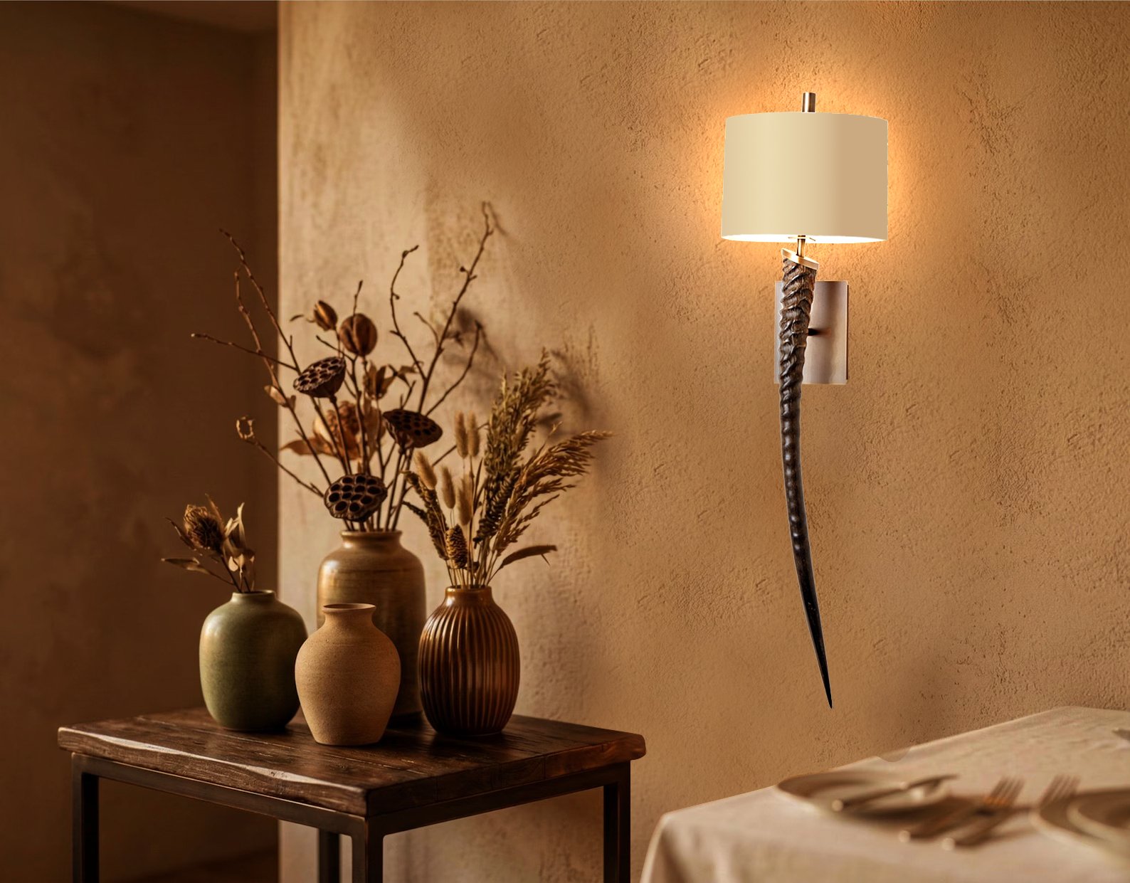 Interior view of a living room with a wall-mounted lamp and a wooden table holding three decorative vases with dried plants, with a beige textured wall background.