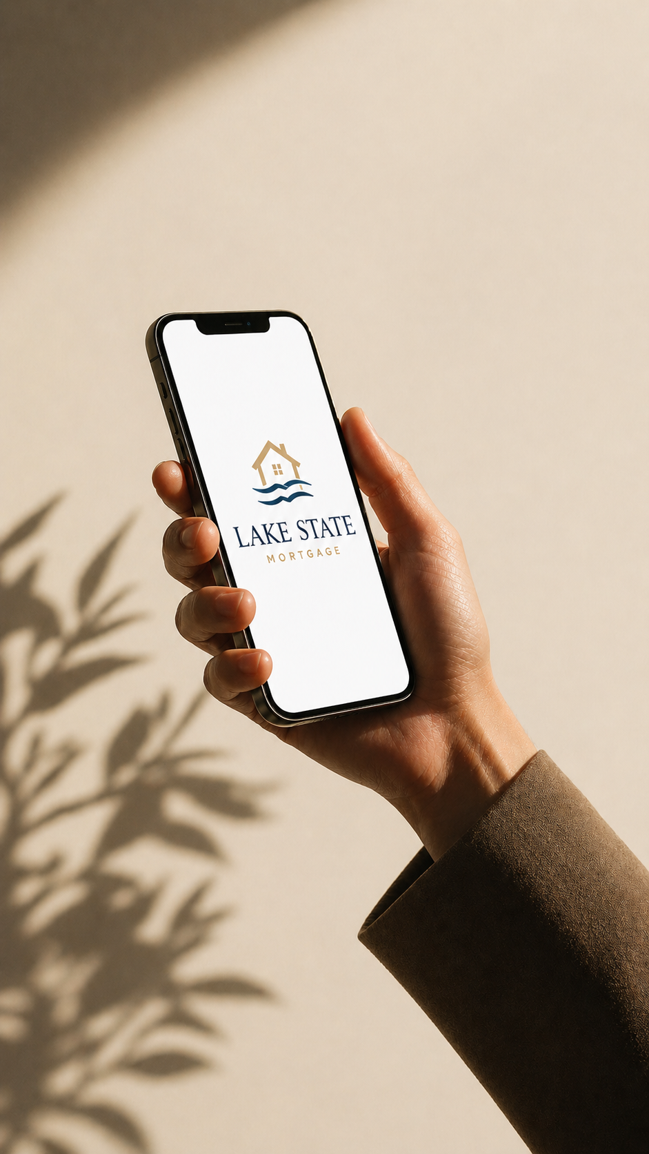 Person holding a smartphone displaying the logo and name of Lake State Mortgage, featuring an icon of a house with waves beneath.