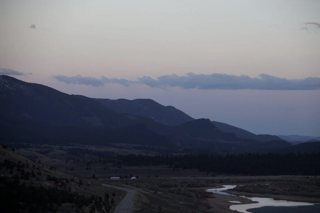 Mountain landscape at dusk with a river flowing through the valley.