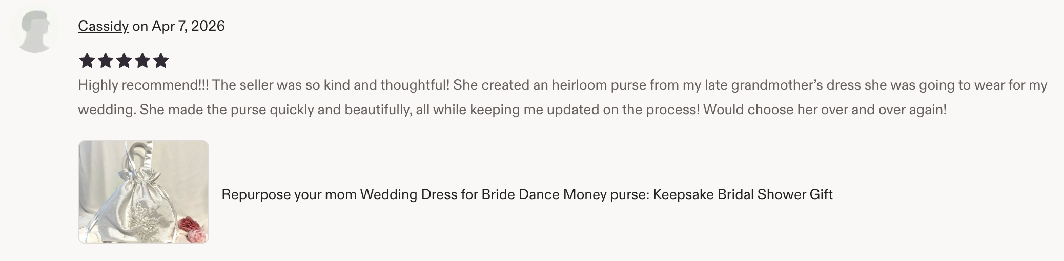 A satin wedding purse with embroidery, tied with a ribbon, and pink flowers beside it.