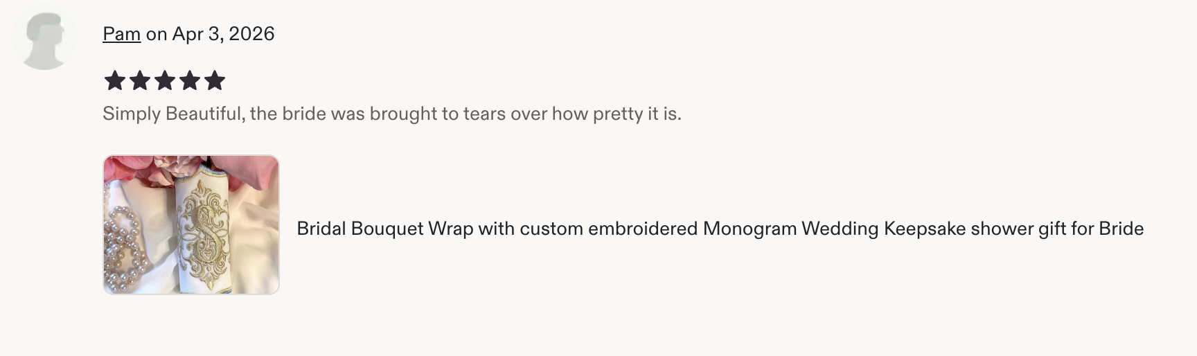 Close-up of a bridal bouquet wrap with embroidery, pearl necklace, and pink flower petals.