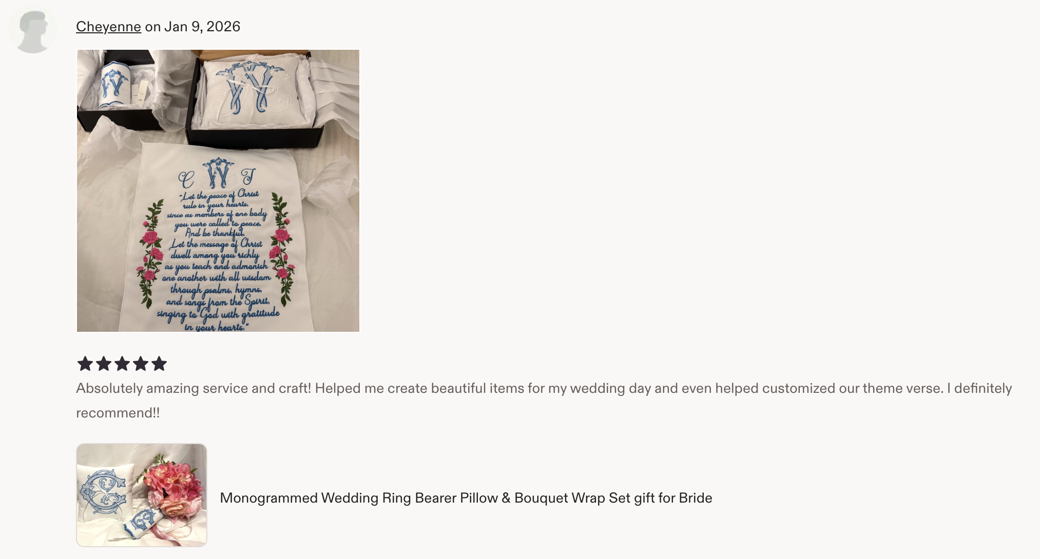 Embroidery of a religious verse with floral decoration on white fabric. The fabric features blue text and is decorated with pink roses and green leaves.