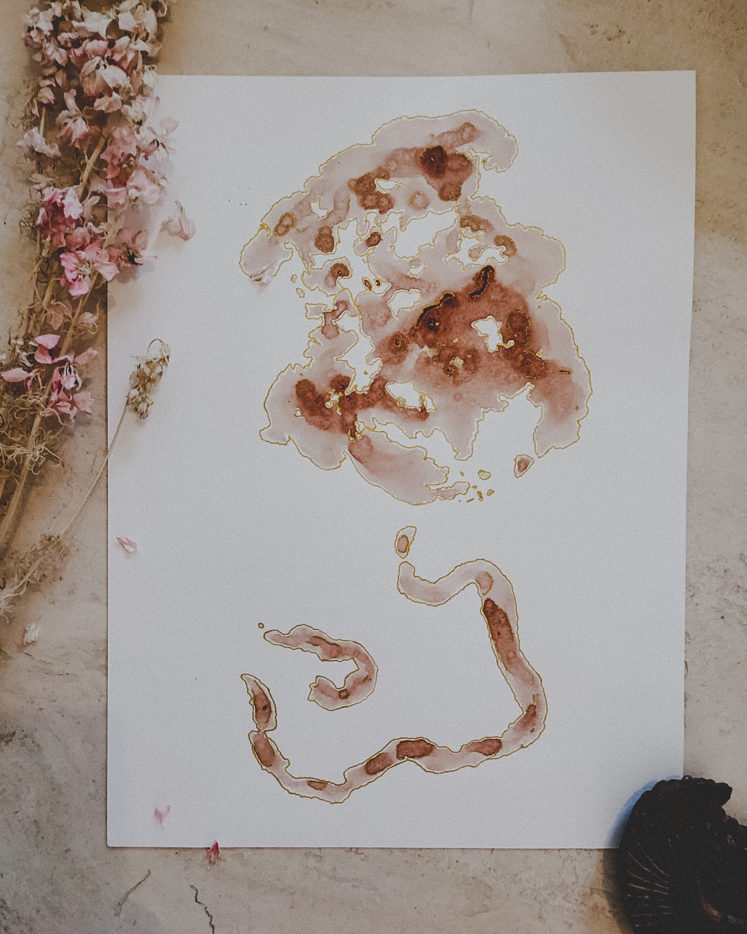 Abstract watercolor artwork on paper with pink and red hues, dried flowers on the left