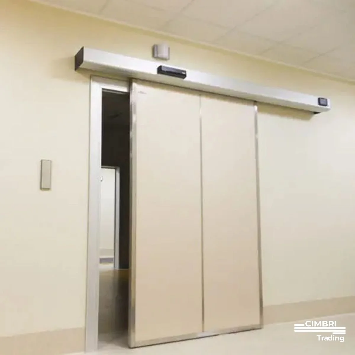 Sliding elevator door with sensors and a control panel on the wall near the door.