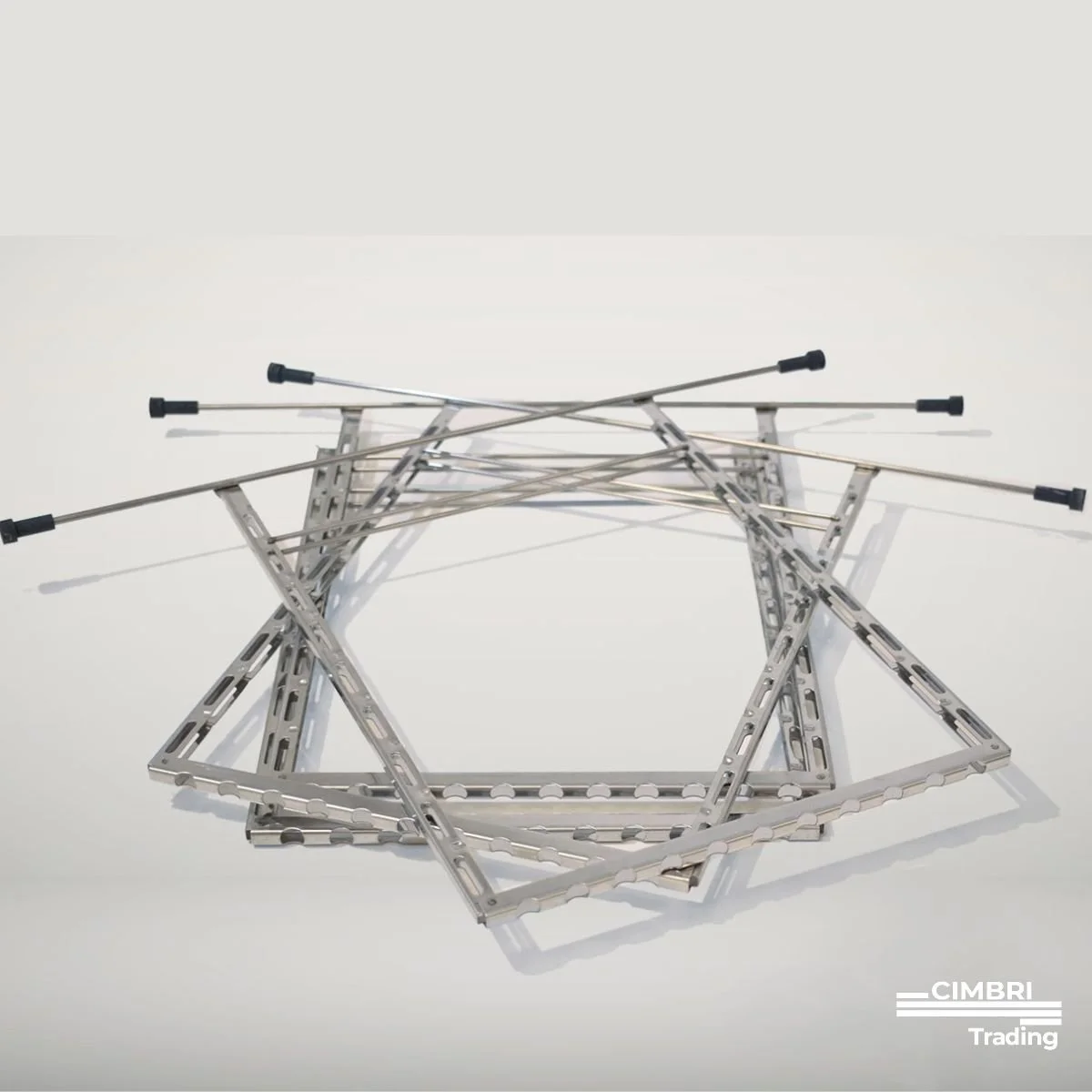 A collection of metallic construction frames and rods arranged on a white surface, with black rubber-tipped rods crossing over each other. The frames are rectangular and made of perforated metal beams, some standing upright and some lying flat.