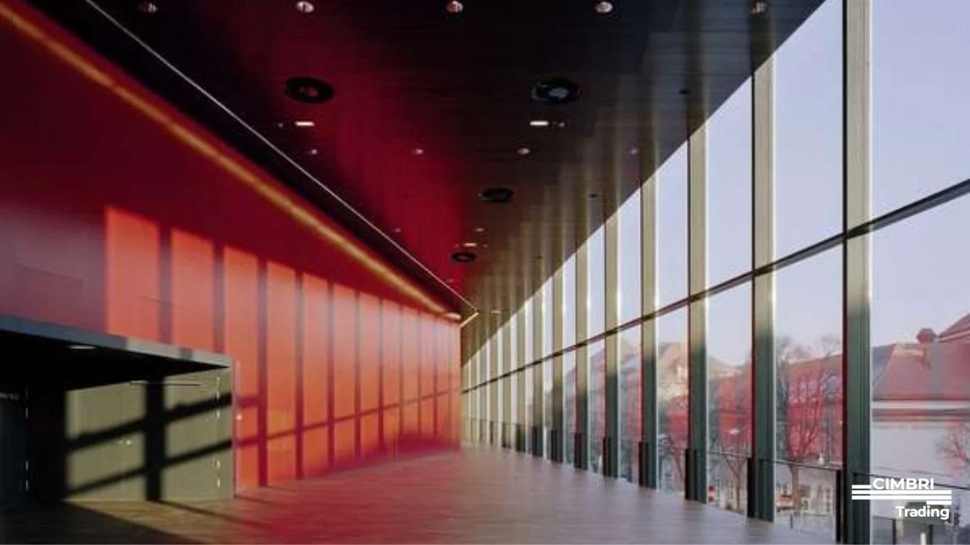 An empty modern interior space with a large glass window wall allowing natural light, with faces of buildings and trees visible outside.