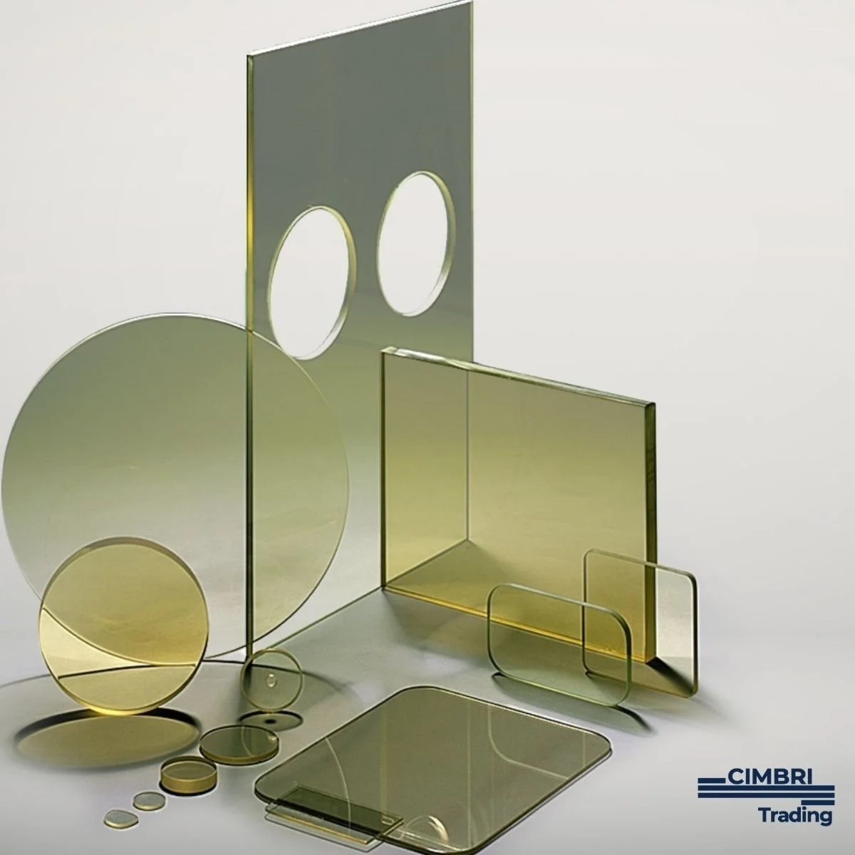 Assorted gold-colored and transparent glass sheets and circles arranged on a white surface, with some overlapping and casting shadows. The logo 'CIMBRI Trading' is in the bottom right corner.