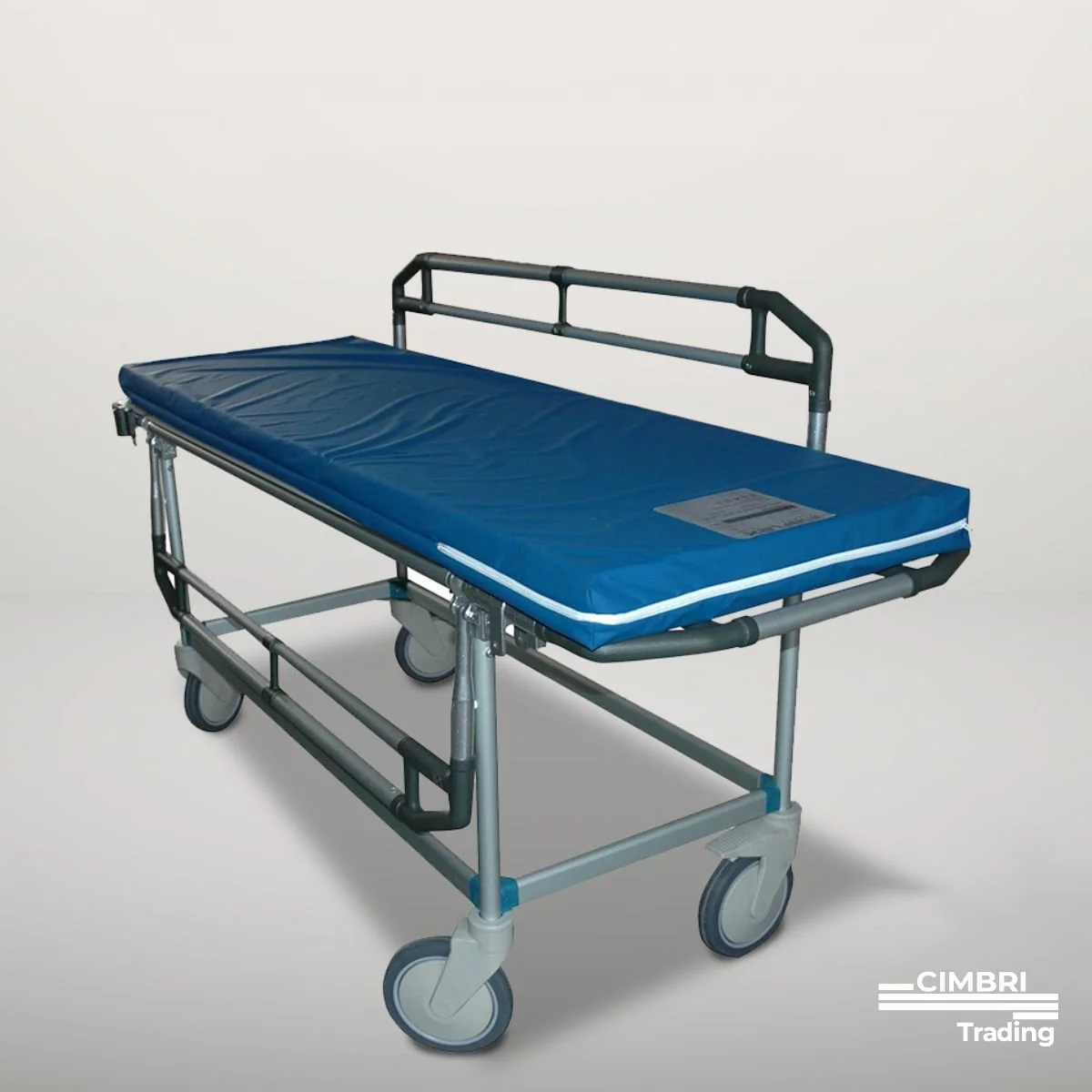 Medical stretcher with a blue padded surface, metal frame, four wheels, and a cardboard label, placed against a plain white background.
