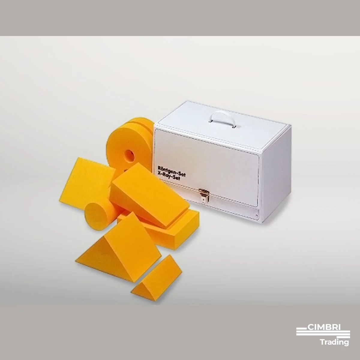 A set of yellow foam shape-building blocks, including cubes, rectangles, triangles, and cylinders, next to a white box labeled 'Rørbyggen-set X-ray-Set' on a white surface.