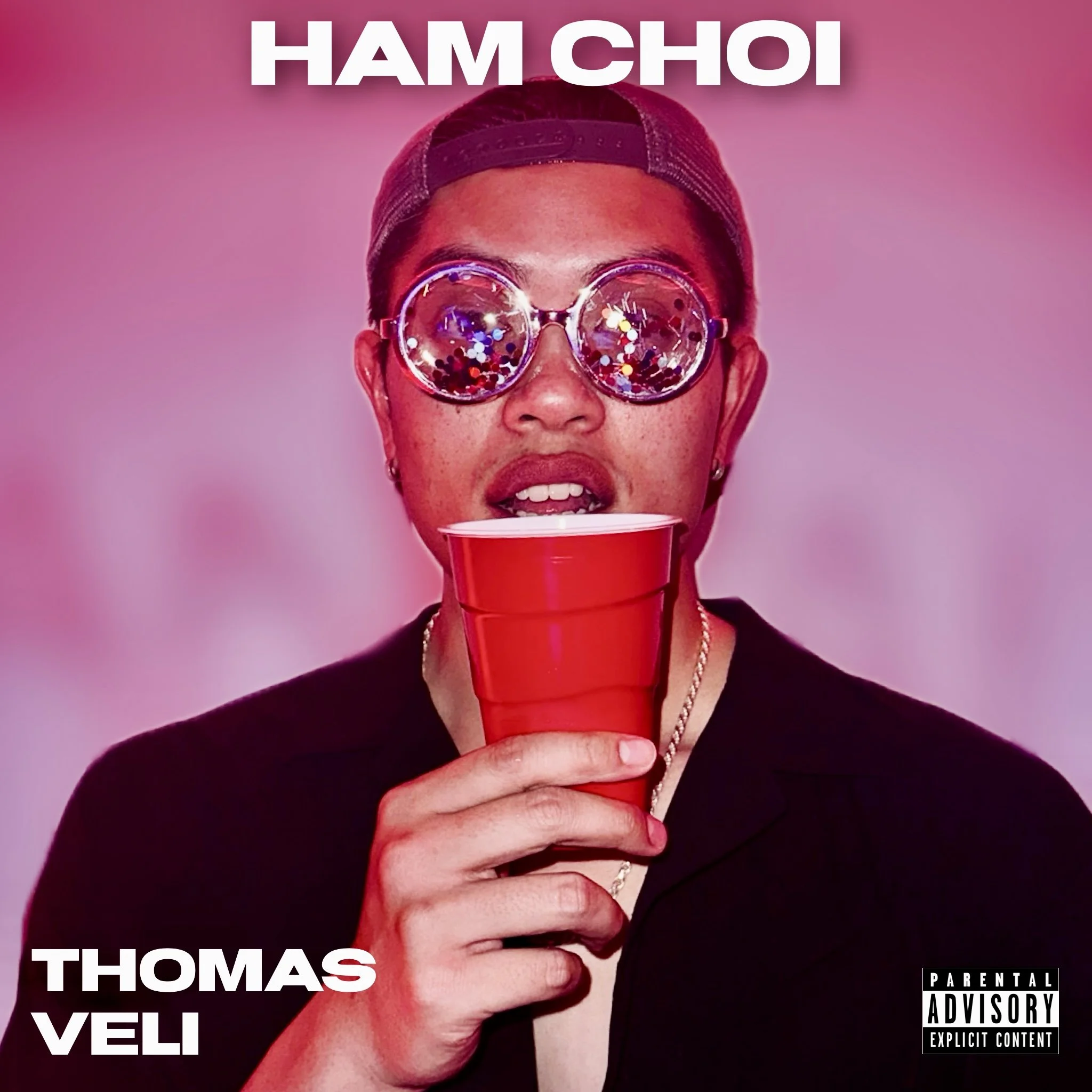 Close-up of a Thomas Veli wearing sunglasses and a backward cap, holding a red cup against a pink background, official cover art his Vietnamese party anthem, "Ham Choi."