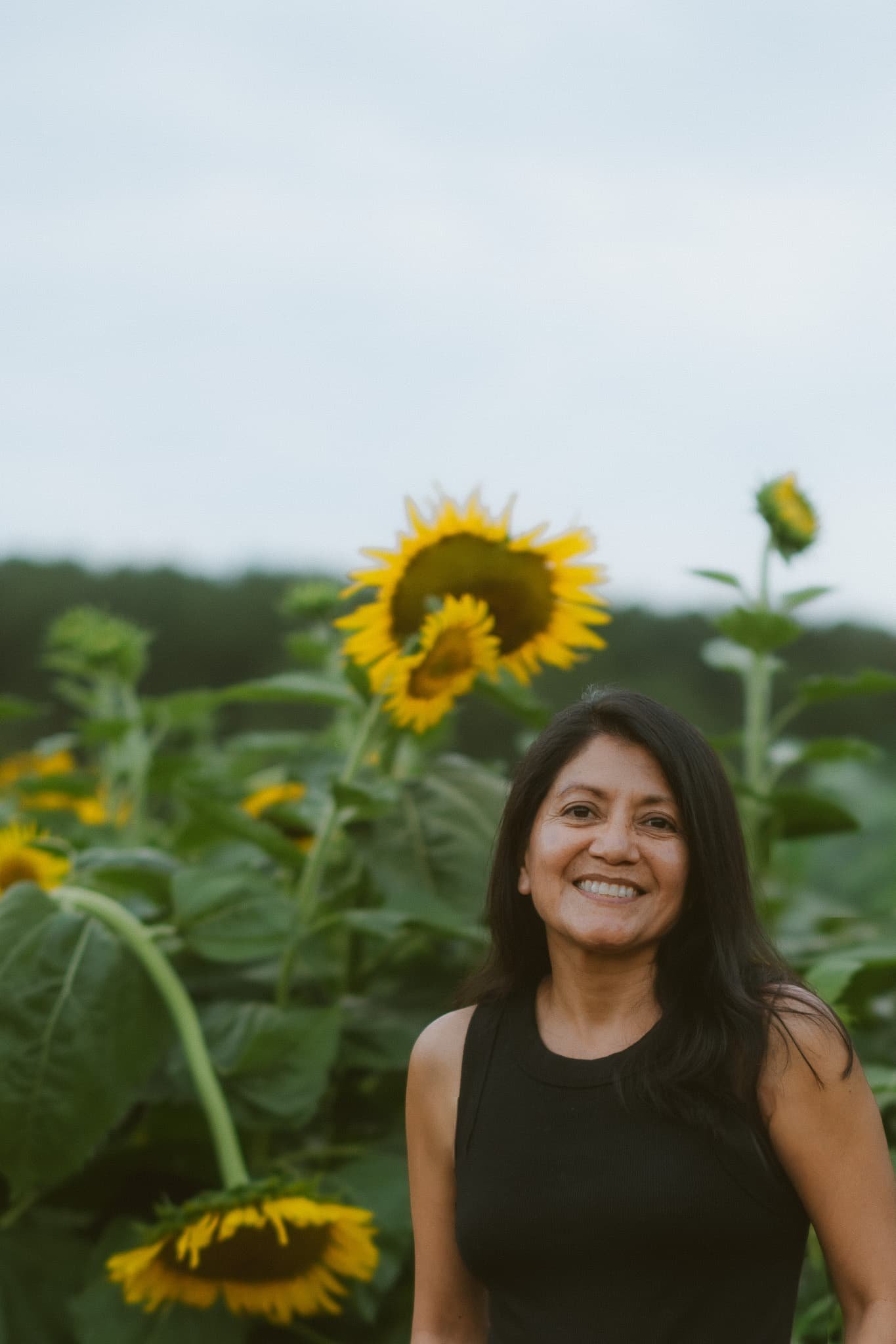 A picture of me smiling surrounded sunflowers.
