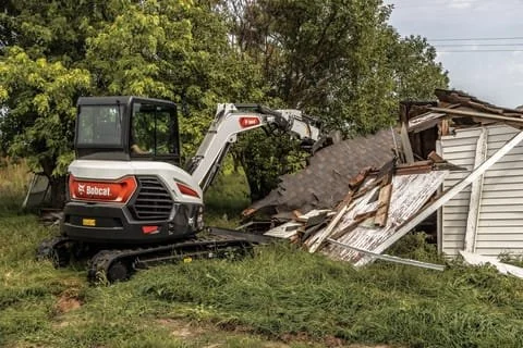 Mini excavator demolishing a small house or shed