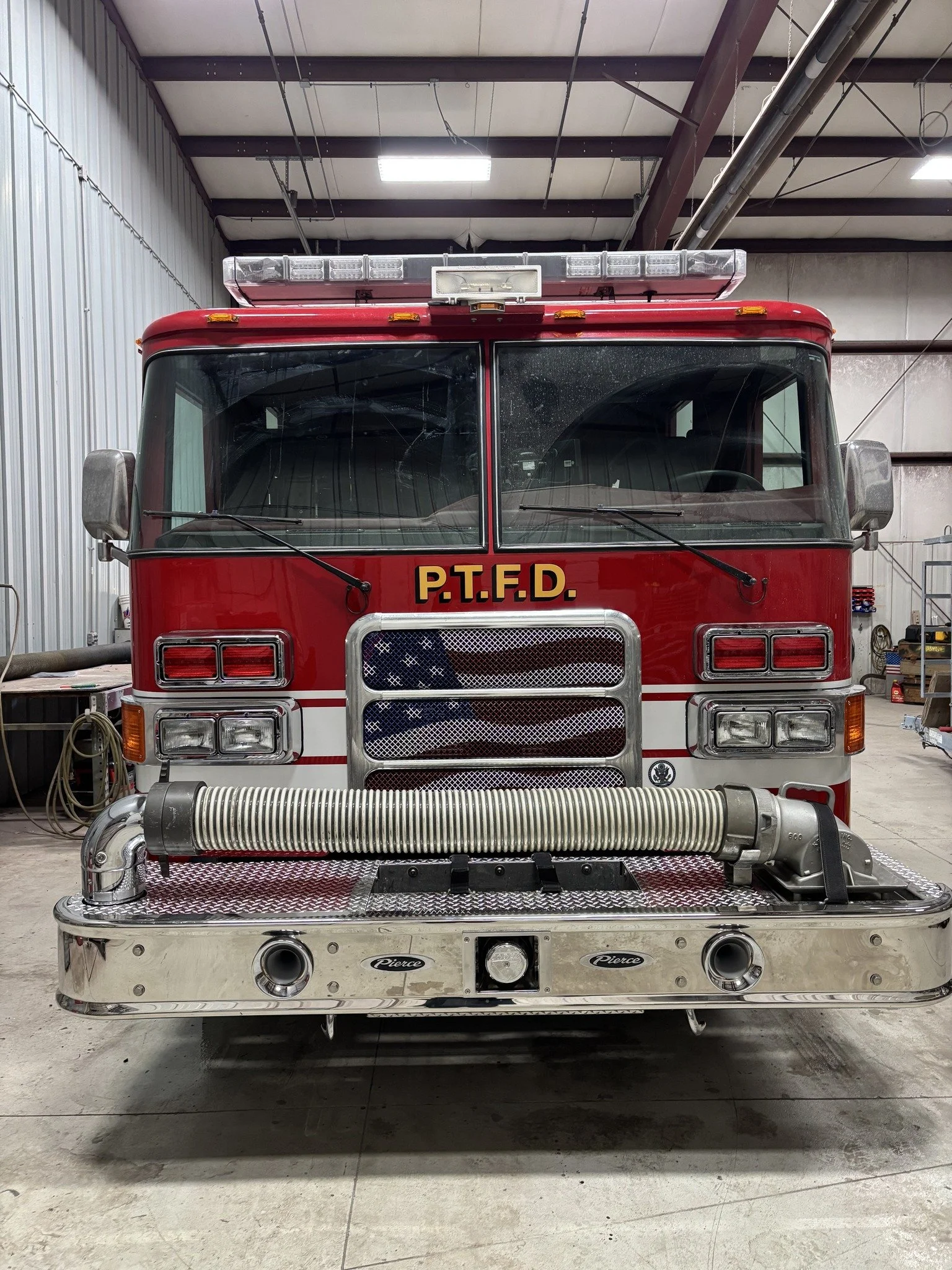 Front view of a red fire truck inside a garage, with equipment attached.