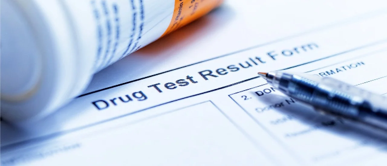 A drug test result form with a pen resting on top of it.