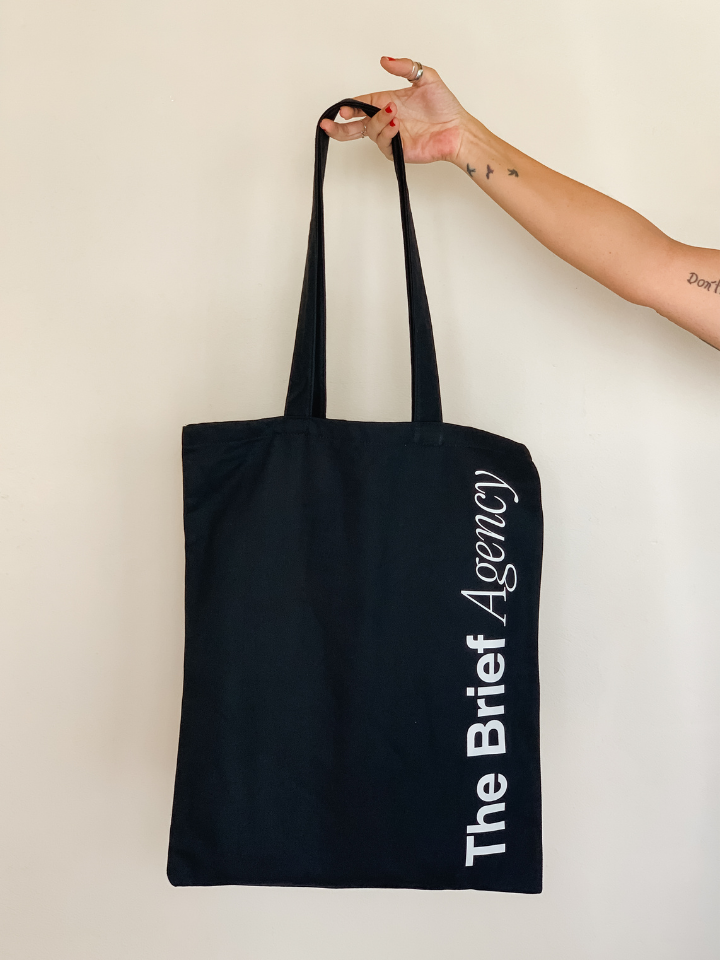 Totebag negra de gabardina con serigrafía The Brief Agency — producción textil para evento Shaolguin Buenos Aires