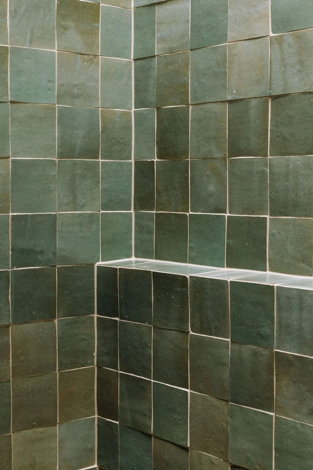 Green tiled corner with small built-in ledge or shelf in a shower or bathroom.