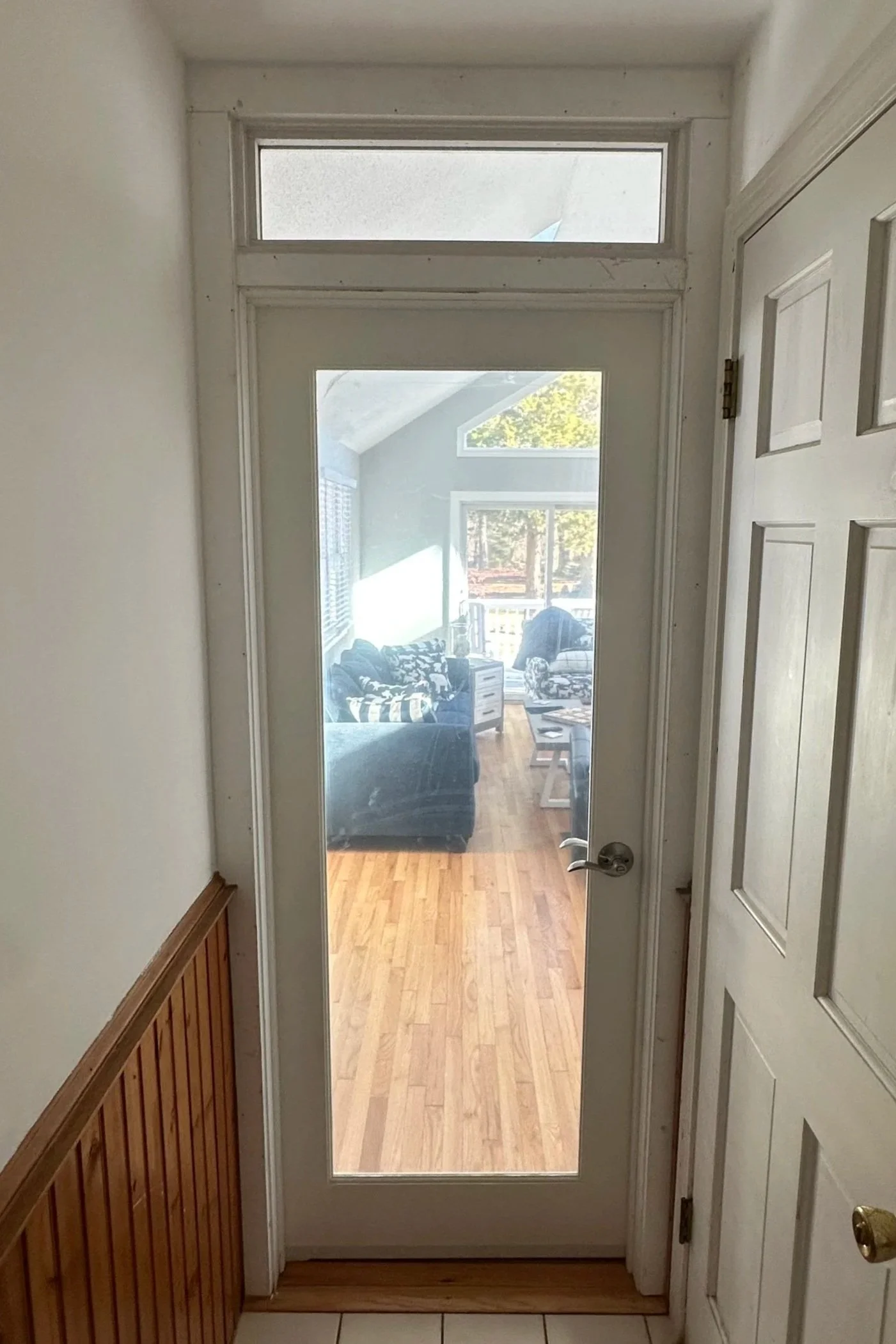 View of a sunroom, seen through a glass-paneled door from an entryway