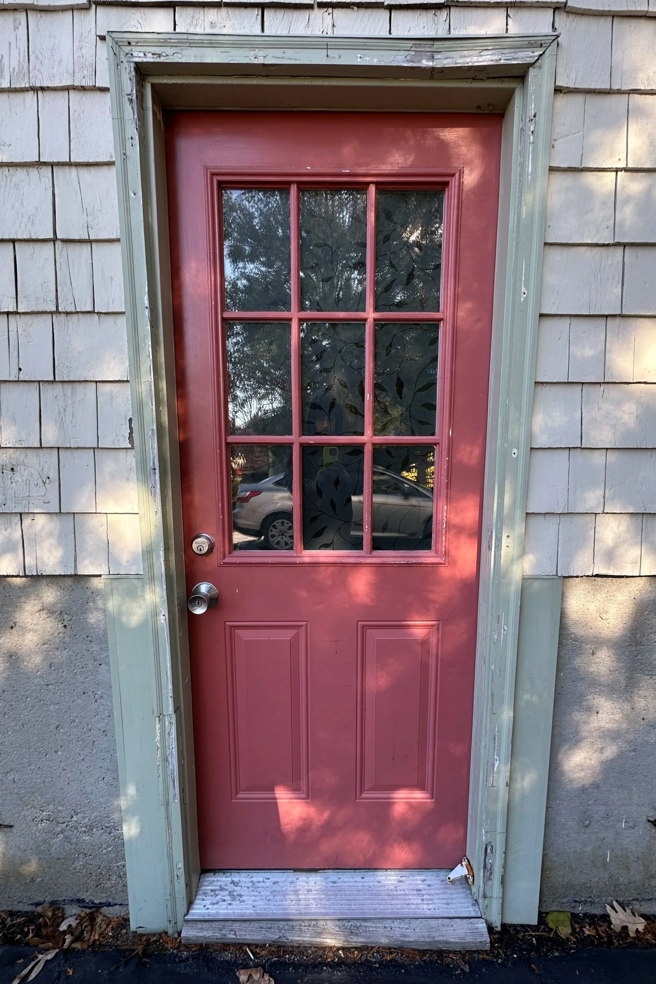 Front view of a red door with divided glass panels in a wooden frame before intall