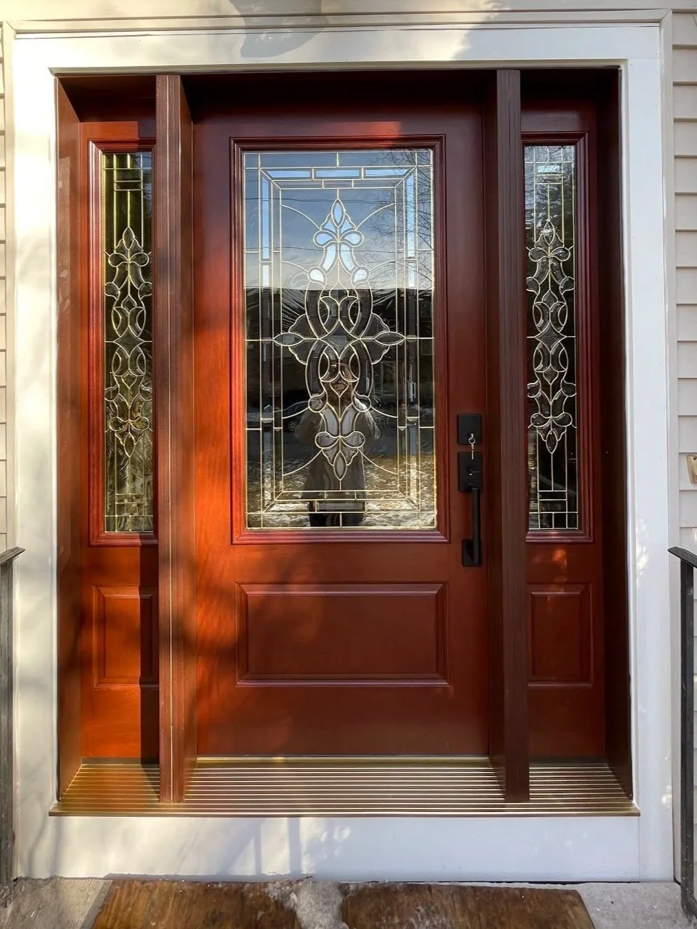 Front door with ornate glass panels and wood finish.