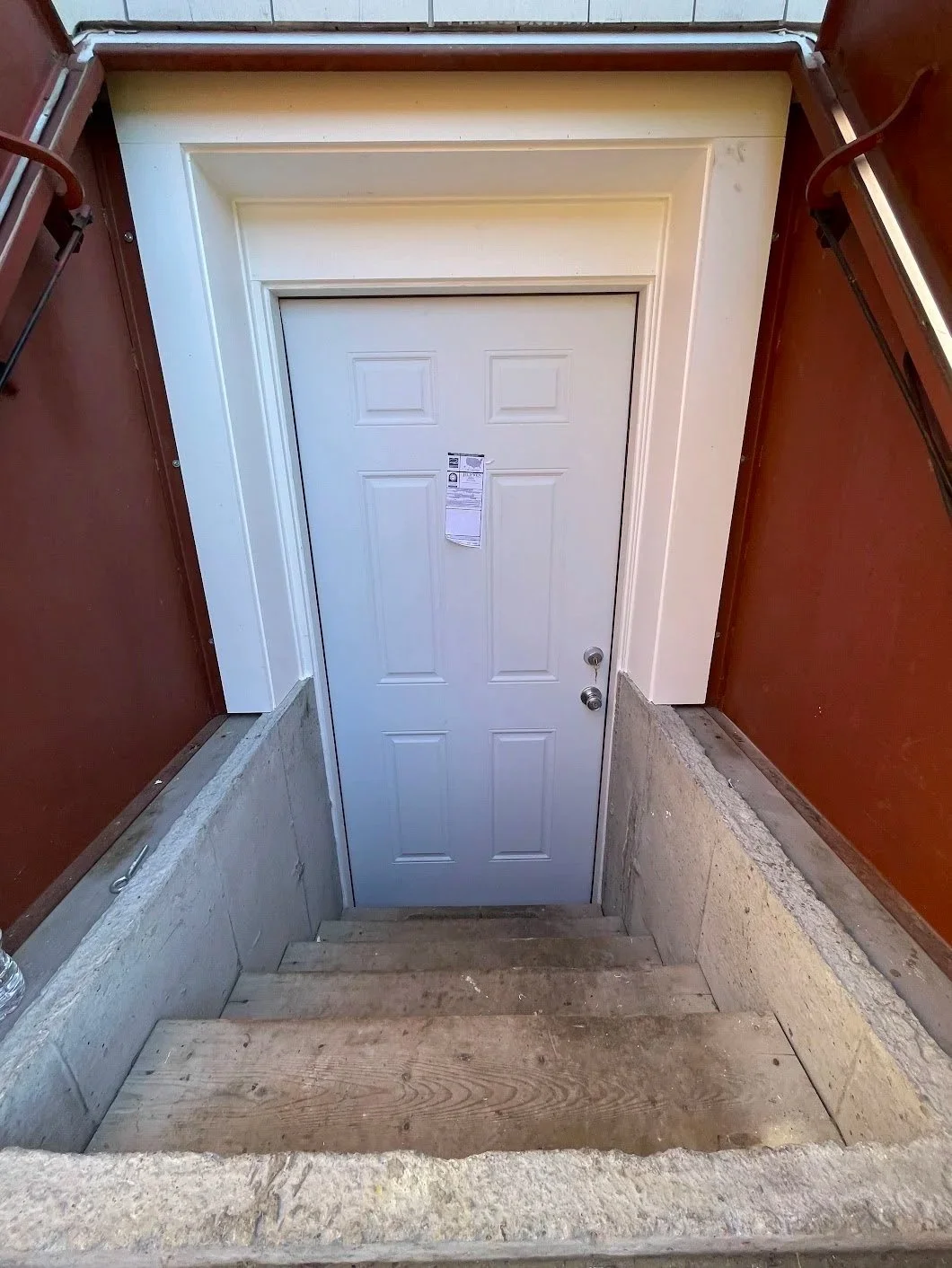 A staircase with wooden steps leading down to a white door at the bottom.