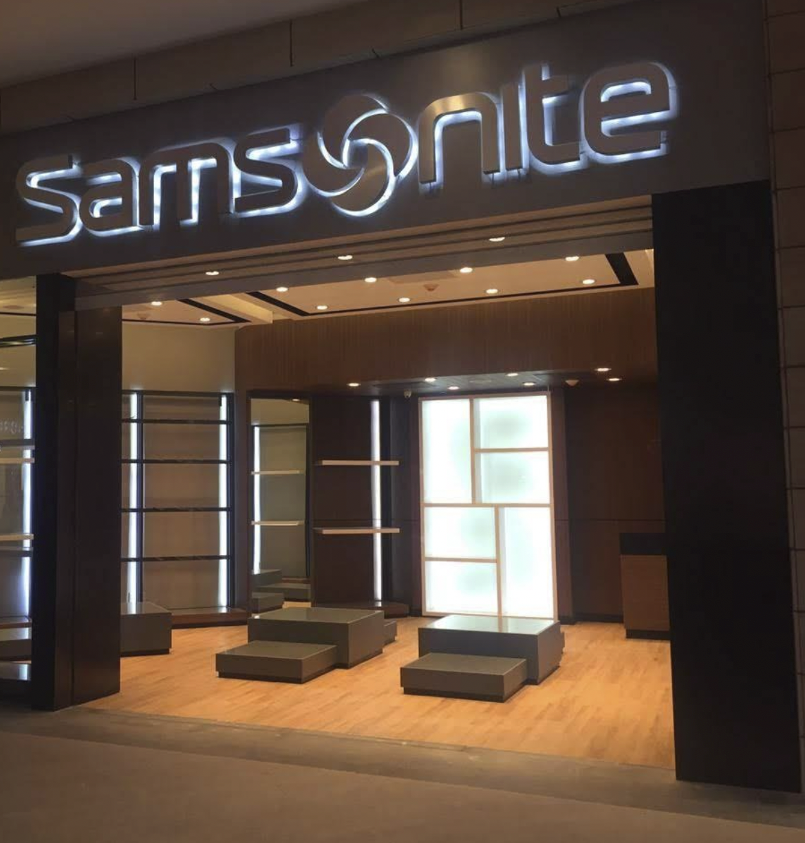 Vista de una tienda de la marca Samsung sin productos exhibidos, con estanterías vacías, piso de madera y luz ambiental cálida.