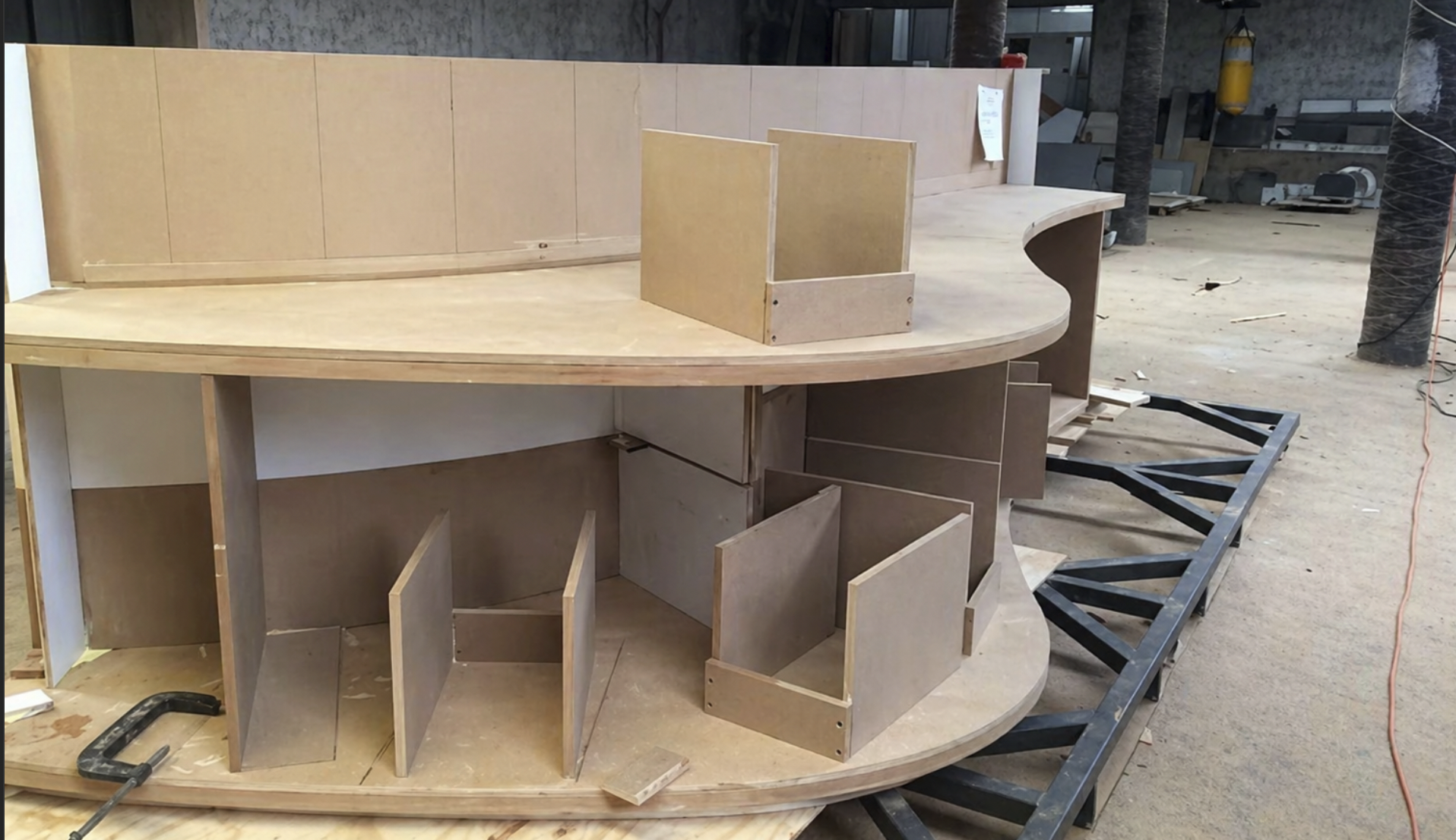 Marco de madera en proceso de construcción, con partes ensambladas y estructura de soporte en el taller.