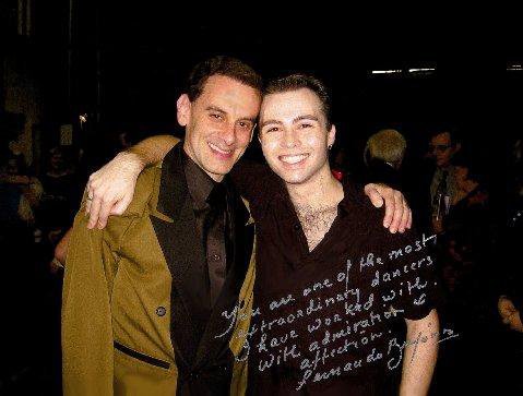 Two young men smiling and posing with their arms around each other at a social event.