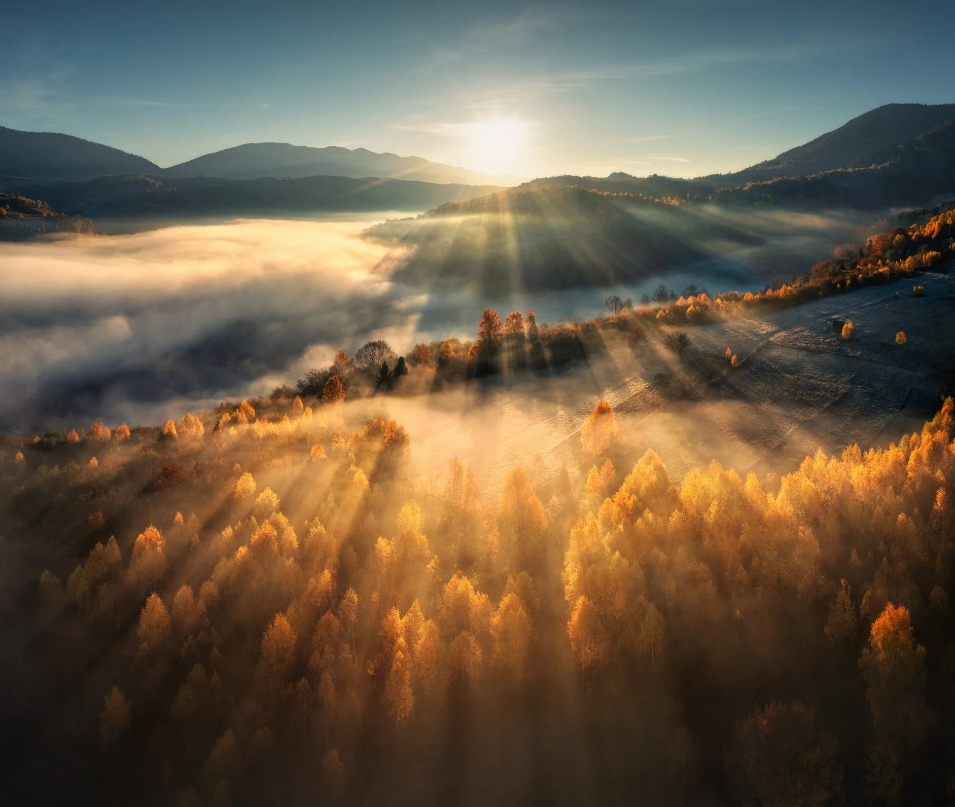 Sunrise breaking over a fog-covered valley, symbolizing Allume Advisory lighting the path to capital.