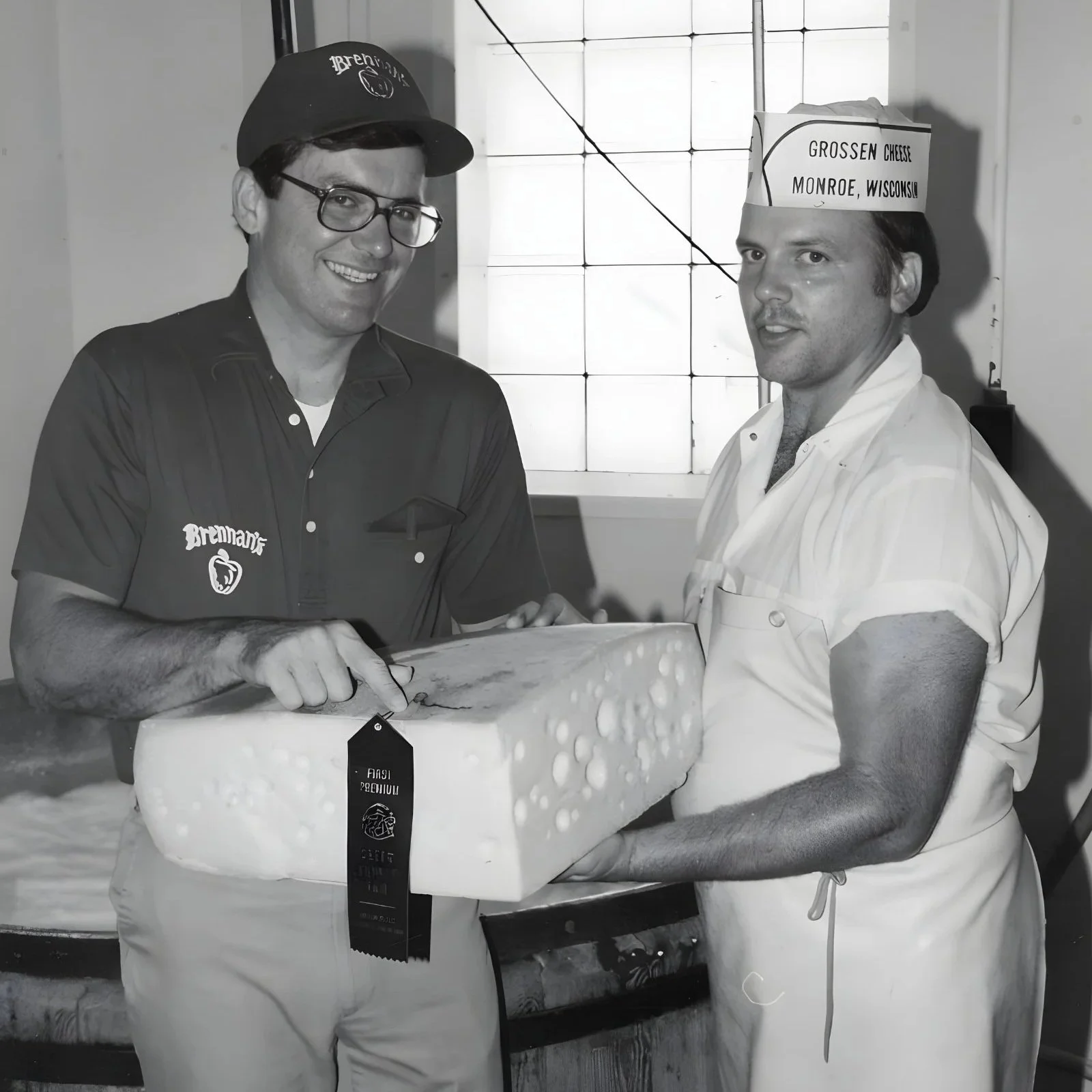 Skip Brennand. shaking hands with a cheesemaker from Grossen Cheese, Monroe, WI. They are holding an award-winning block of cheese