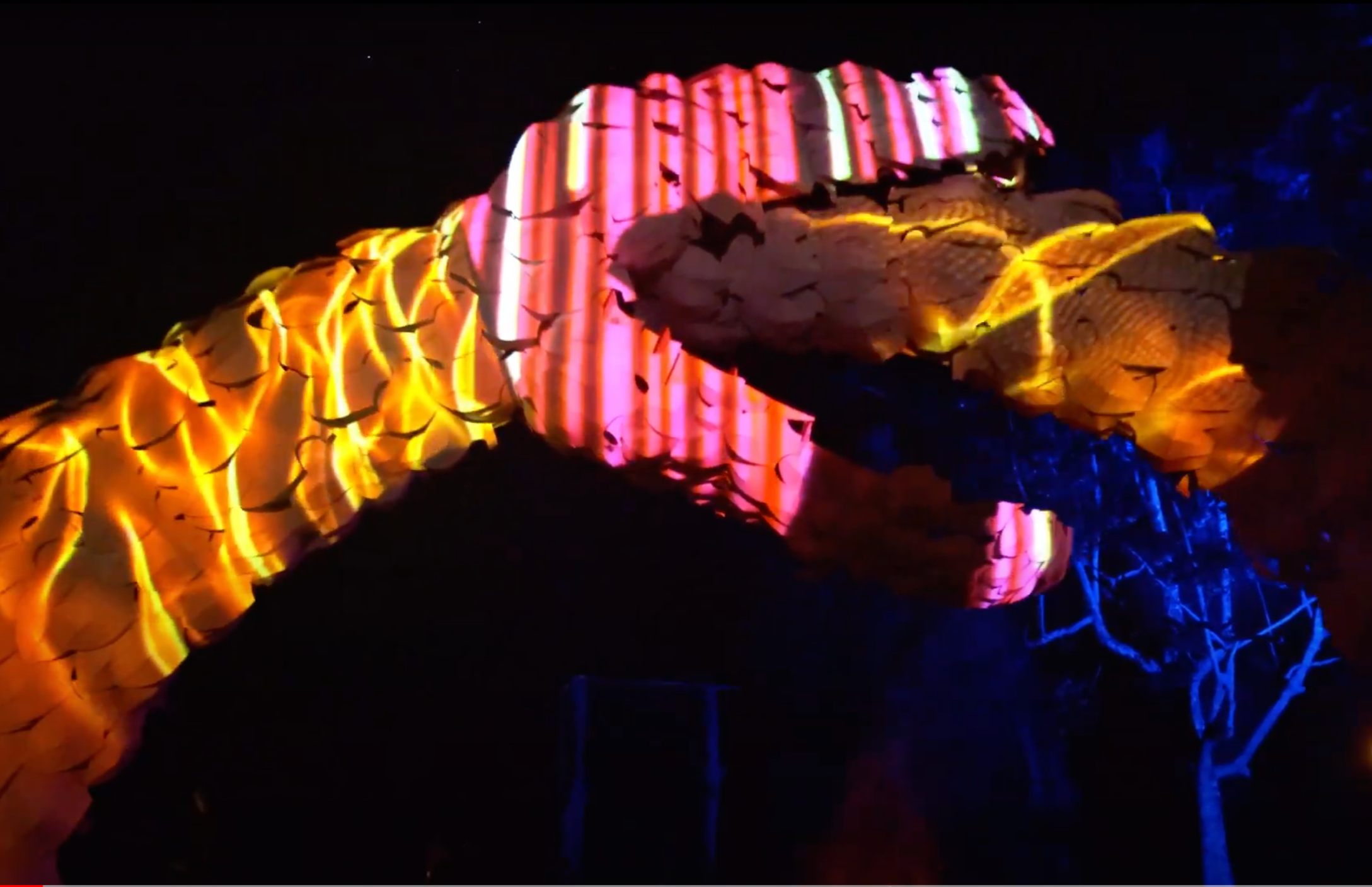 Colorful light projections on the side of a mountain at night.