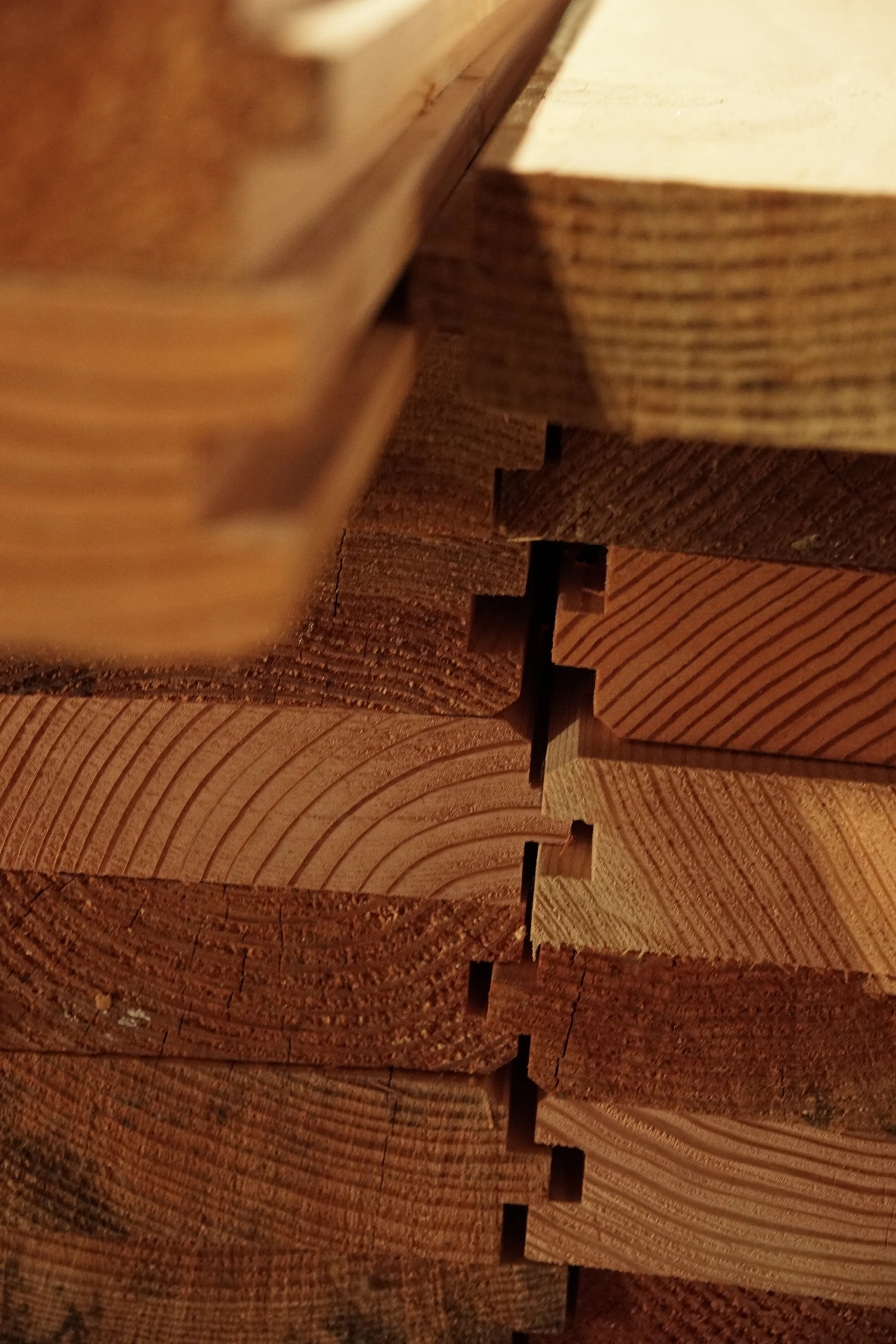 Close-up image of stacked cut wooden planks or beams, showing the wood grain and texture.