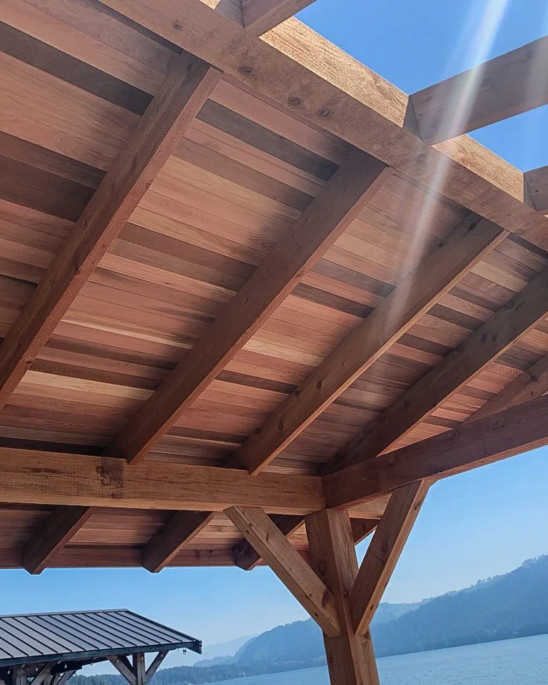 Looking up at a wooden pergola with a clear blue sky and distant mountains in the background.Great Central Timber Milling Port Alberni Custom Milling Sawmill