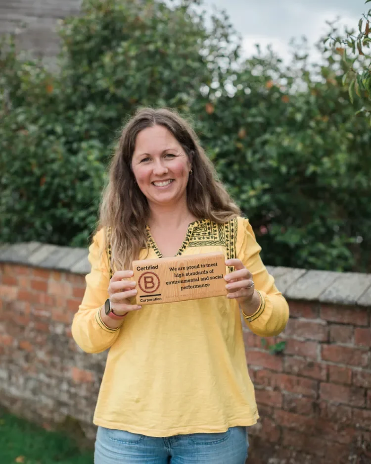 Laura Slack, Planet & Purpose smiling holding a wooden Certified B Corporation block