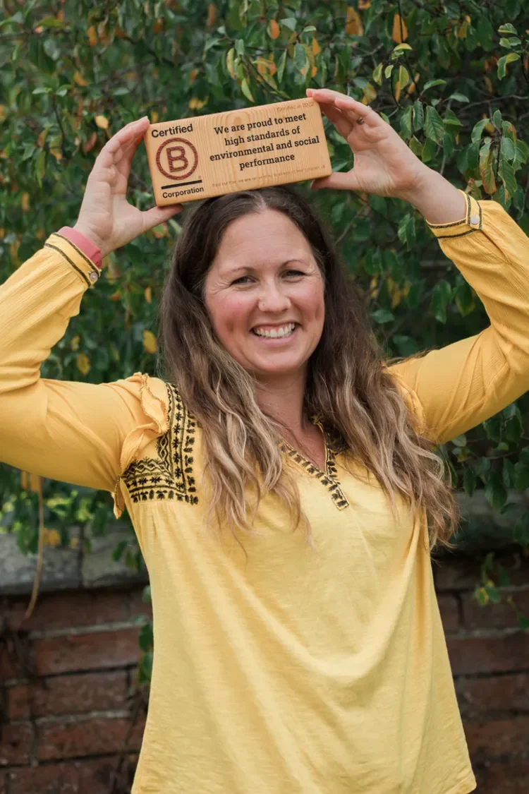 Laura Slack, Planet & Purpose smiling holding her Certified B Corporation wooden block over her head