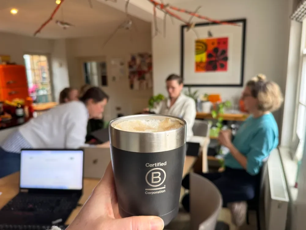 Laura Slack, Planet & Purpose holding a B Corporation mug with the B Bolder Collective group in the background
